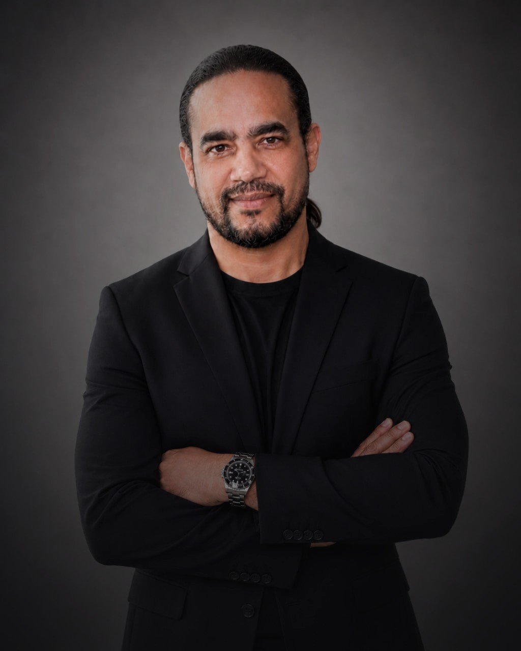 Retrato profissional de Andre Richest Costa, de blazer preto e braços cruzados